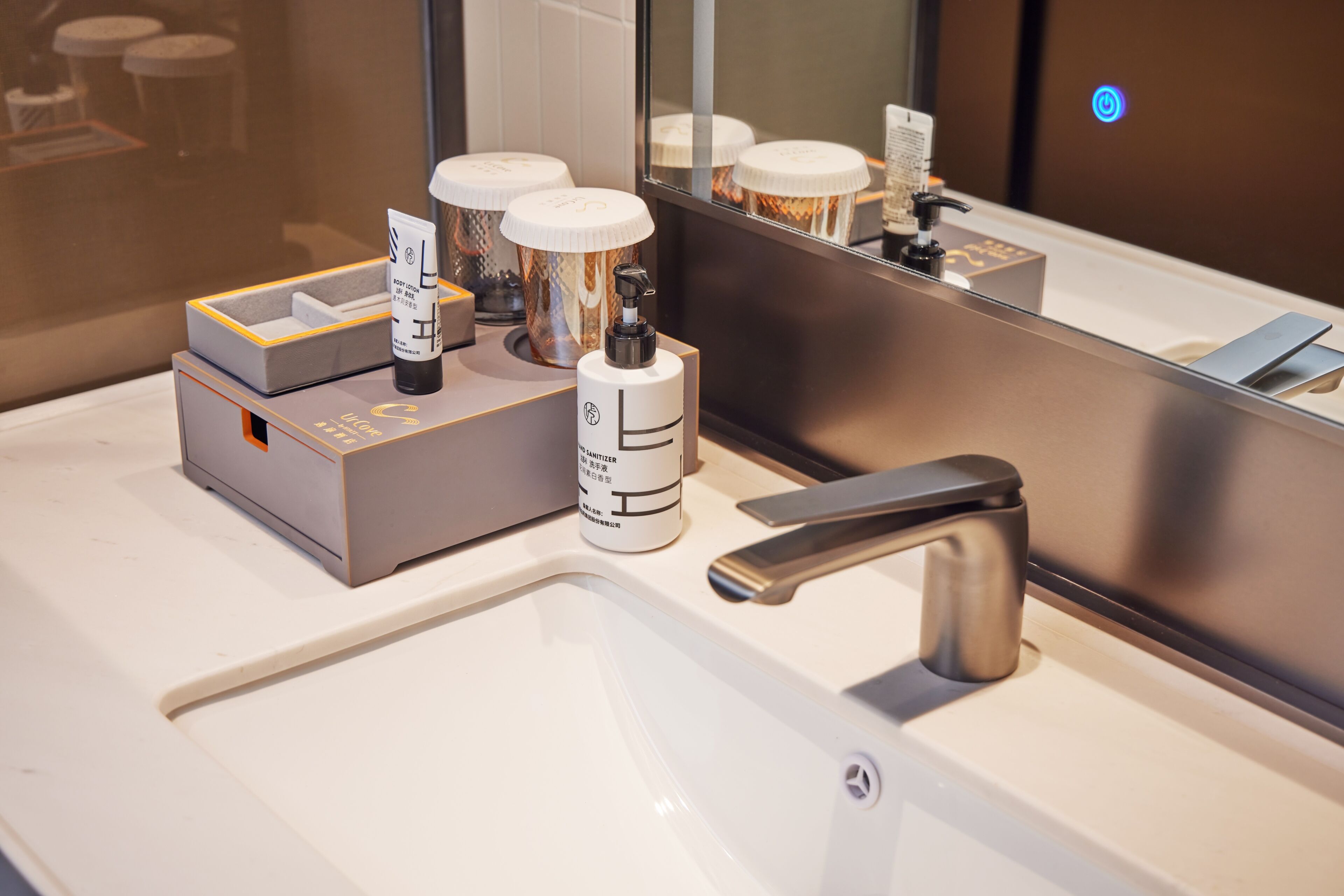 A modern bathroom with a large mirror, a sleek faucet, and various toiletries on the counter.