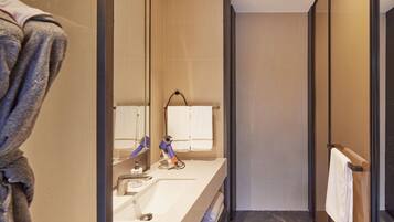 A modern bathroom with a large mirror, a sink, a towel rack, and a shower area.