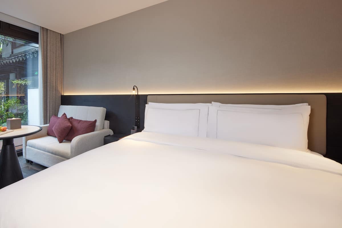 Ein Hotelzimmer mit Bett, Stuhl, Tisch und Lampe.
