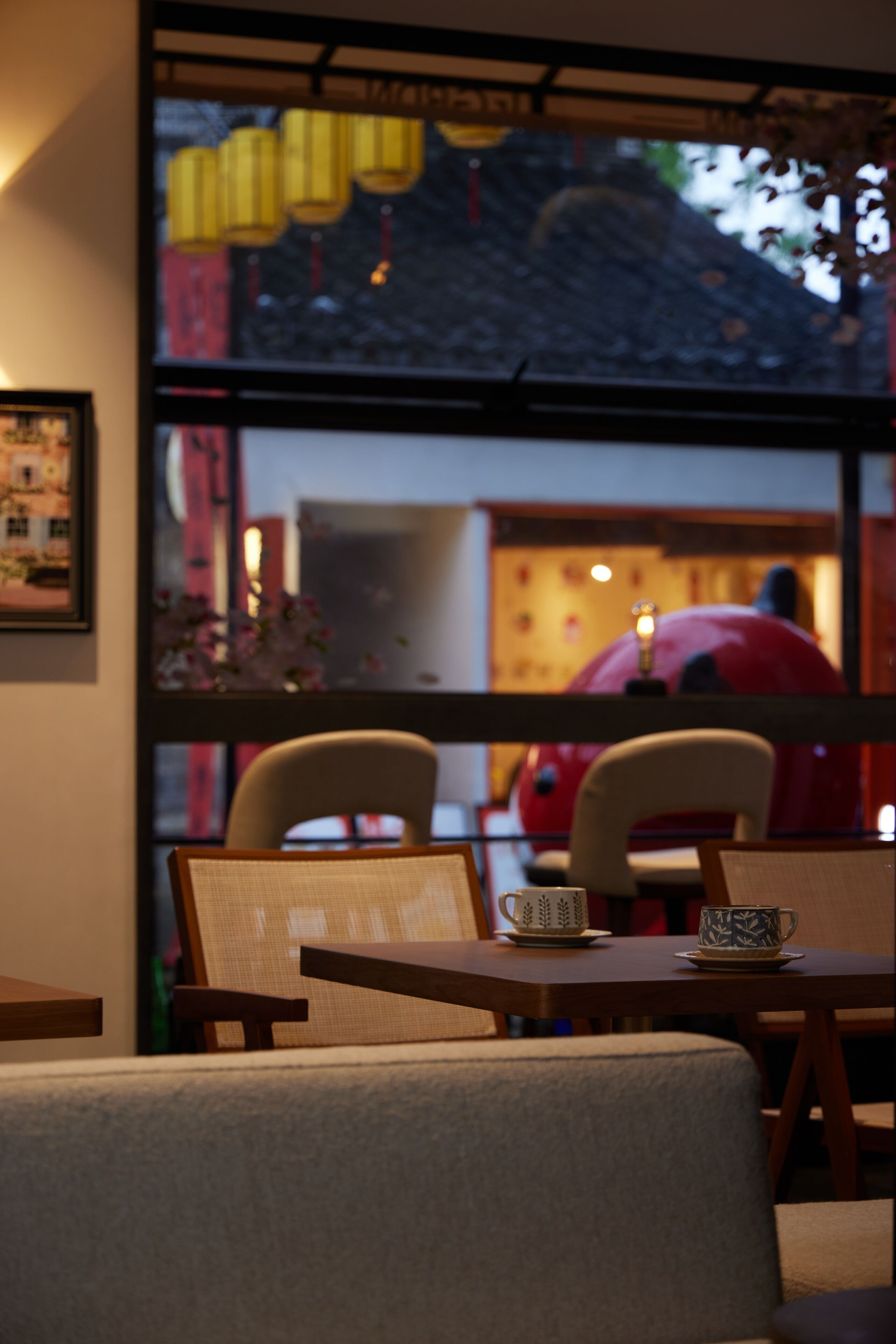 A dining area with a table and chairs, a window with a view of the outside, and a framed picture on the wall.