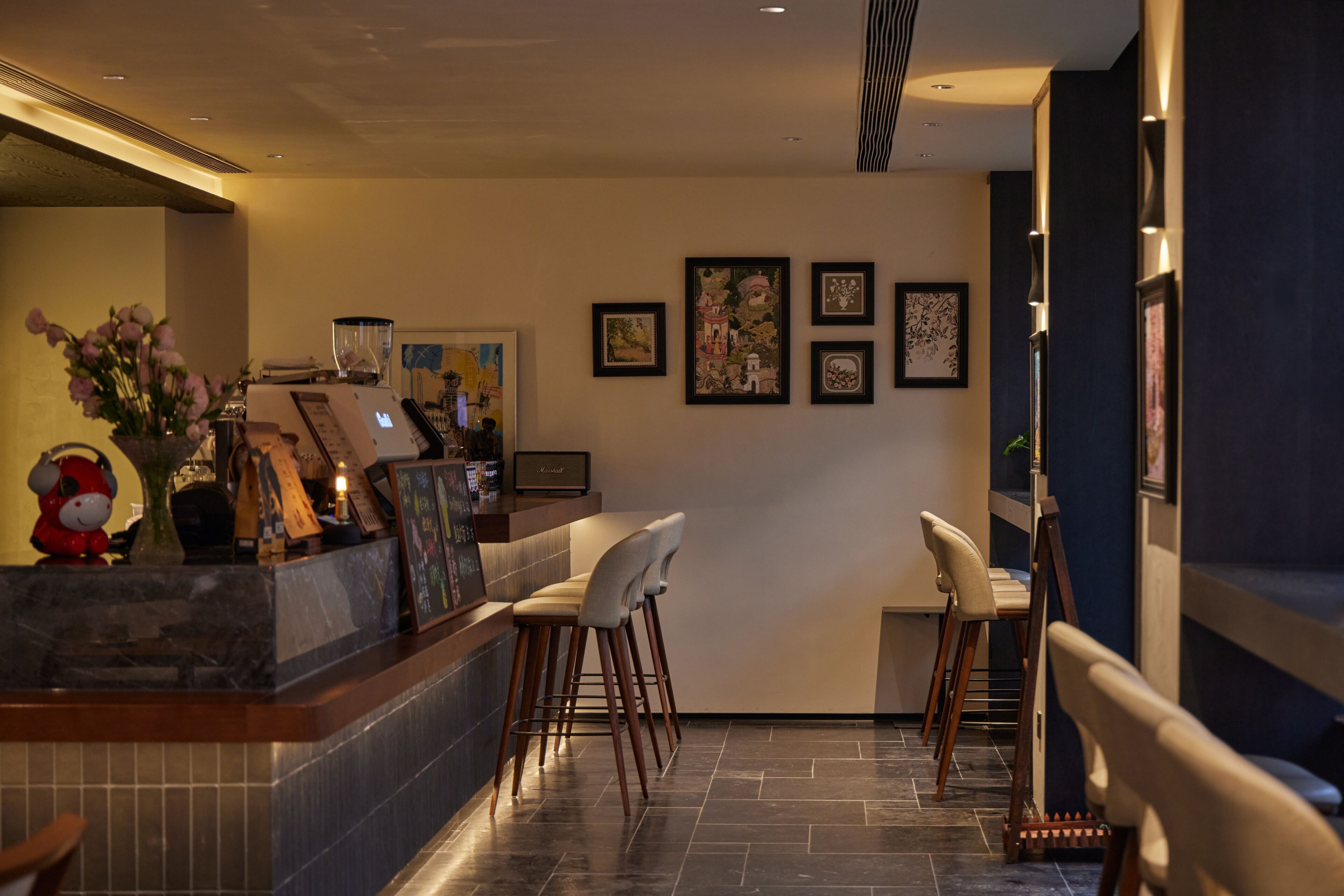 A bar area with stools, a counter, and framed artwork on the wall.