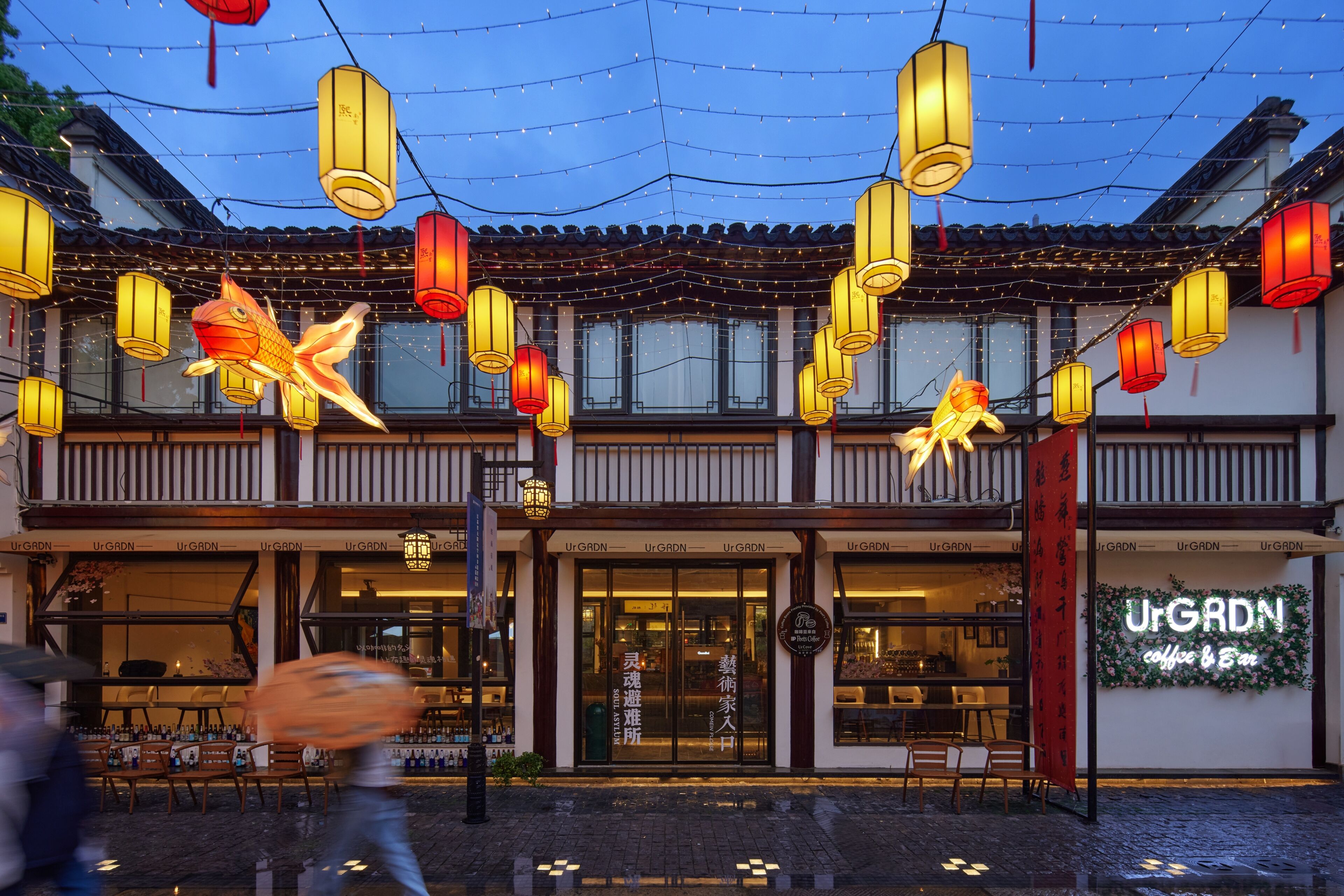 A traditional building with a storefront, outdoor seating, and hanging lanterns.
