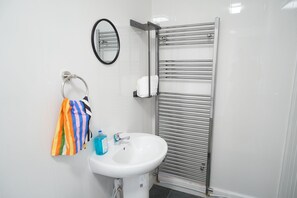 A bathroom with a white sink, a towel rack with a colorful towel, a mirror, and a towel rack with a towel. - Fabulous 4-bedroom Apartment in enjoyable Newcastle with Free Parking (Newcastle upon Tyne)