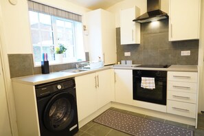 A compact kitchen with a washing machine, oven, and a window with a view. - Fabulous 4-bedroom Apartment in enjoyable Newcastle with Free Parking (Newcastle upon Tyne)