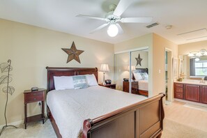 Un dormitorio con una cama de madera, una mesita de noche, un aparador y un ventilador de techo.