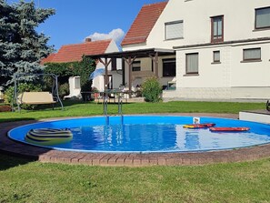 A swimming pool with a wooden deck, a lounge chair, and a small garden area. - Große Ferienwohnung in Niedergurig mit Großem Ga by Interhome (Bautzen)