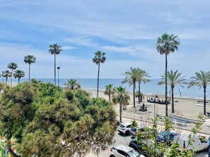Ein Strand mit Palmen, geparkten Autos und blauem Himmel.