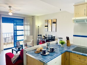 Eine moderne Küche mit blauen Fliesen, einer eingebauten Kochstelle und einem Essbereich mit Tisch und Stühlen.