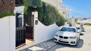 A white building with a gated entrance, a BMW parked in front, and a clear blue sky. - Apto. Barbacana by At Home Costa del Sol (Caleta de velez)