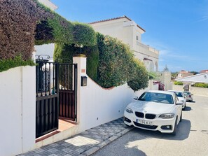 Ein weißes Gebäude mit einem eingenetzten Eingang, ein BMW davor, und ein klarer, blauer Himmel.