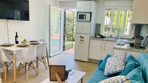 A modern living space with a dining area, kitchen, and a sofa with patterned cushions. - Apto. Barbacana by At Home Costa del Sol (Caleta de velez)