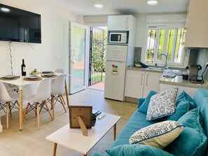 Ein moderner Wohnraum mit Essbereich, Küche und einer Couch mit gemusterten Kissen.