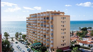 A multi-story hotel with balconies, a parking lot, and a view of the sea. - Apto. Pescamar by At Home Costa del Sol (Torrox)