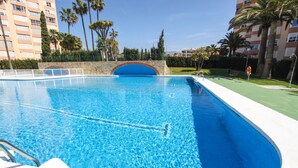 A swimming pool with a stone arch bridge, surrounded by palm trees and a multi-story building. - Apto. Pescamar by At Home Costa del Sol (Torrox)