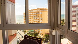 A view from a window overlooking a parking lot, a building with balconies, and a body of water. - Apto. Pescamar by At Home Costa del Sol (Torrox)