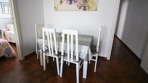 A dining area with a table and chairs, a painting on the wall, and a bed with a colorful bedspread in the background. - P. Andaluz 670 by At Home Costa del Sol (Torrox)