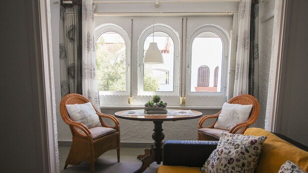 A room with a round table, two wicker chairs, a sofa with floral cushions, and three arched windows. - P. Andaluz 670 by At Home Costa del Sol (Torrox)