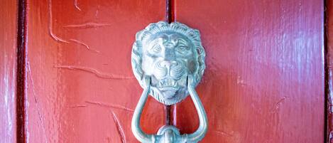 A red door with a metal lion head knock.