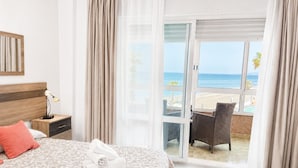 Une chambre d’hôtel avec un lit, une table de chevet, une lampe, une serviette et une vue sur la plage.