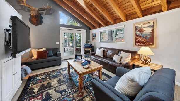 Un salon chaleureux avec une cheminée, une tête de wapiti fixée au mur et un tableau encadré représentant le lac Tahoe.