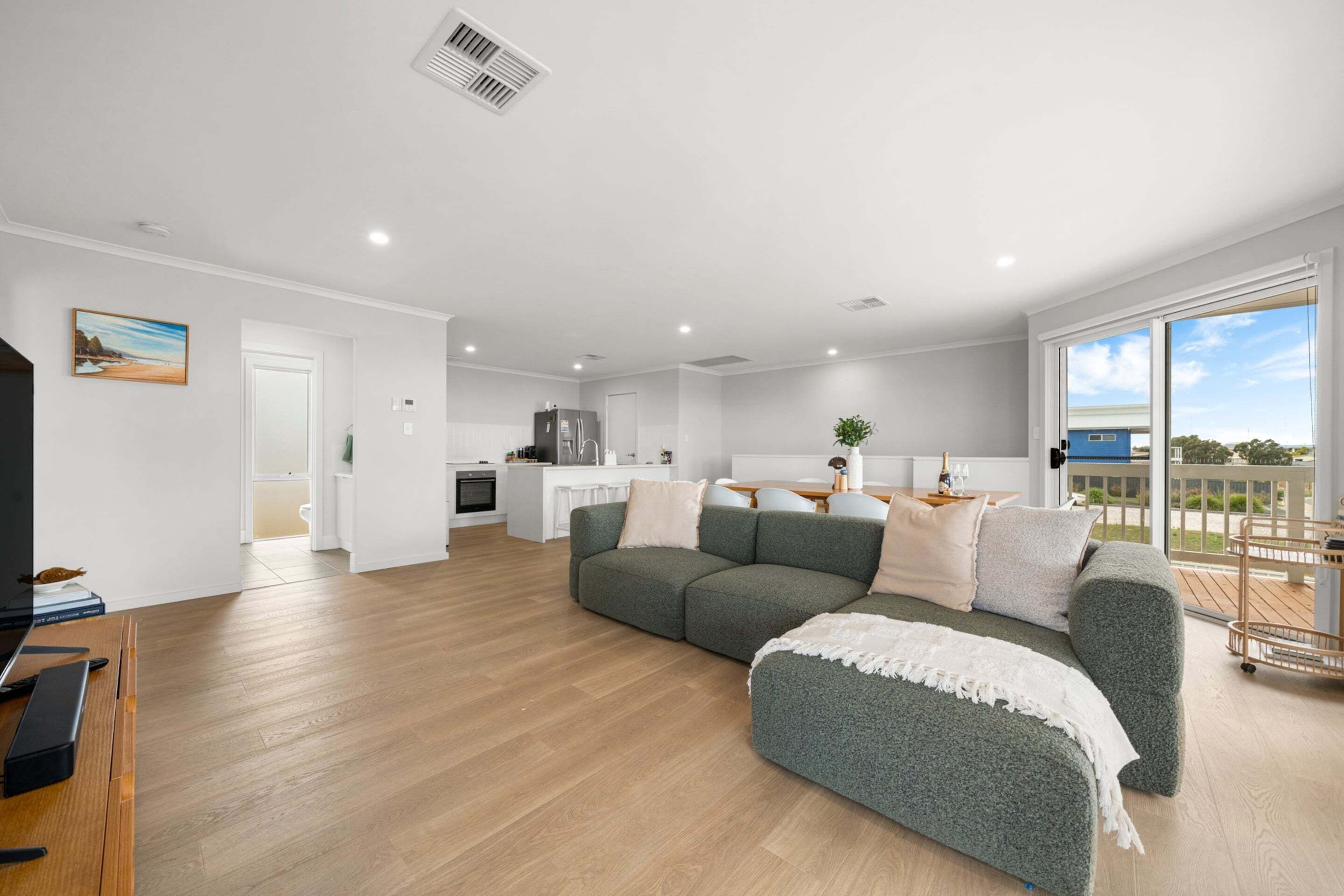 A modern living room with a sectional sofa, a TV, and a wooden floor.