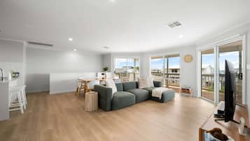 A modern living room with a sectional sofa, a dining area, and a TV.