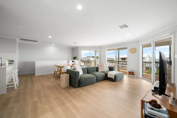 A modern living room with a sectional sofa, a dining area, and a TV.
