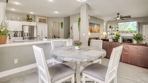 A modern kitchen with a dining area, a chandelier, and a flat-screen TV. - Screened Lanai & Yard! Family Getaway in Apopka (Apopka)