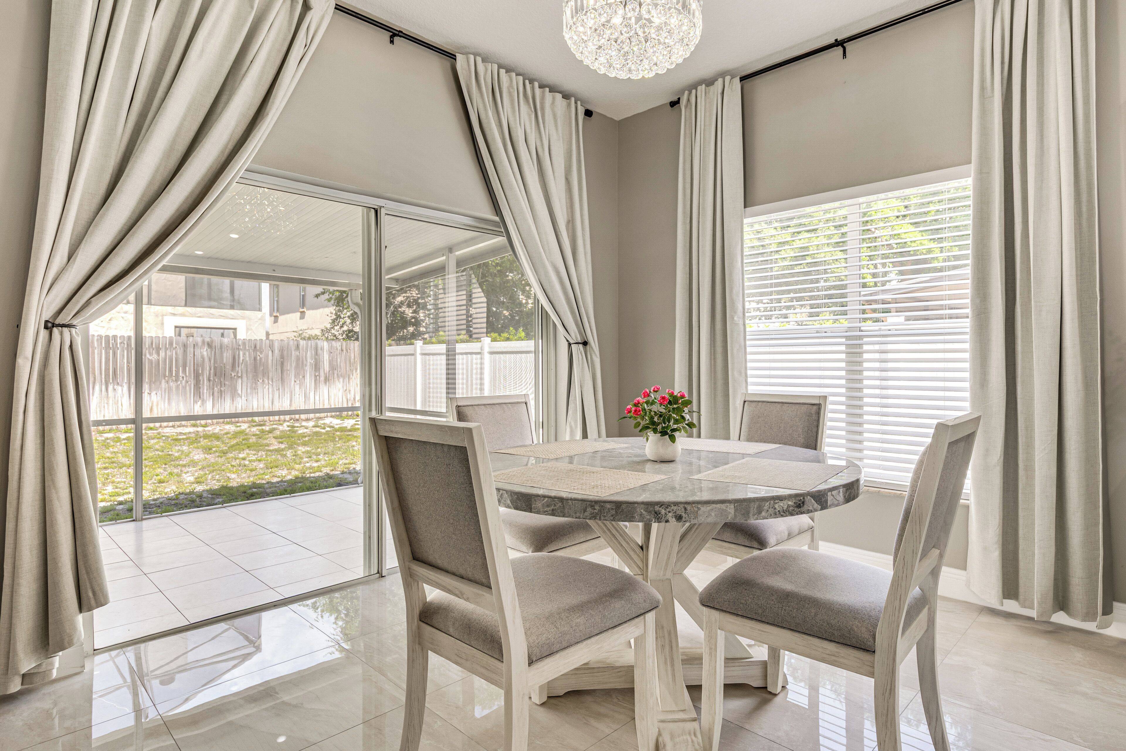 A dining area with a round table, four chairs, and a vase with flowers.