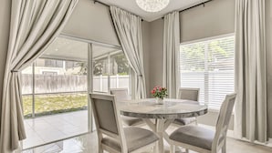 A dining area with a round table, four chairs, and a vase with flowers. - Screened Lanai & Yard! Family Getaway in Apopka (Apopka)