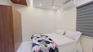 A bedroom with a bed, a wardrobe, an air conditioning unit, and a window with blinds. - IZEL CASA (Kanayannur)
