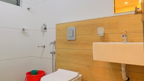 A modern bathroom with a white toilet, wooden vanity, and a mirror. - IZEL CASA (Kanayannur)