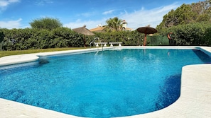 A clear blue swimming pool with a white deck, surrounded by lush greenery and a clear sky. - Stylish Holiday Apartment in Torrox Park with Sea View (Torrox)