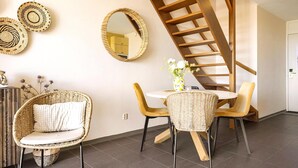 Um interior moderno com escada em espiral, móveis de vime e espelhos decorativos.