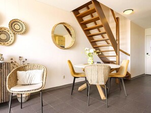 Ein modernes Interieur mit Wendeltreppe, Korbmöbeln und dekorativen Spiegeln.