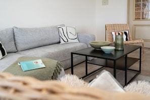 A living room with a grey sofa, a black coffee table, a wicker chair, and a bowl on the table. - Penthouse F23 - Penthouse for 7 people with a unique view over Sylt, (Sylt)