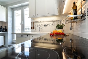 A modern kitchen with white cabinets, a black countertop, and a backsplash with floral patterns. - Penthouse F23 - Penthouse for 7 people with a unique view over Sylt, (Sylt)
