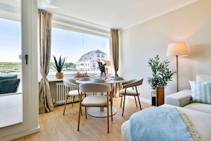 Ein modernes Hotelzimmer mit Essbereich, einer Sitzecke, einer Lampe und Blick auf ein Gebäude.