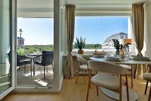 Een eetruimte met een tafel voor vier personen, uitzicht op de stadsgezicht en een balkon met terrasmeubels.