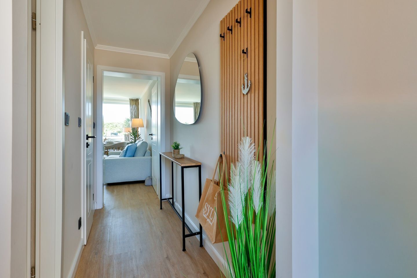 Ein Flur mit Holzboden, einer Couch, einem Spiegel und einer an der Wand befestigten Holzvertäfelung mit Ankerdekor.