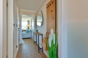 Ein Flur mit Holzboden, einer Couch, einem Spiegel und einer an der Wand befestigten Holzvertäfelung mit Ankerdekor.