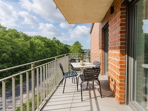 Ein Balkon mit Tisch und Stühlen, einer Weinflasche und einem Glas.