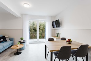 Ein modernes Wohnzimmer mit einer Couch, einem Couchtisch und einem Essbereich mit Stühlen.