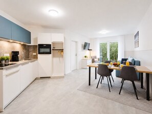 Uma cozinha moderna com forno embutido, máquina de café e área de refeições com mesa e cadeiras.