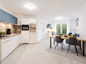 Eine moderne Küche mit Backofen, einer Kaffeemaschine und einem Essbereich mit Tisch und Stühlen.