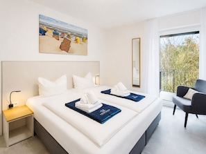 A hotel room with a large bed, a nightstand, a chair, a balcony with a view, and a painting on the wall. - MEERholung Vacation Rental 3.6 with Balcony for up to 5 Guests, 400 m from the Sea - House (Cuxhaven)