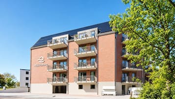 Ein mehrstöckiges Gebäude mit Ziegelverkleidung, Balkonen und blauem Himmel.