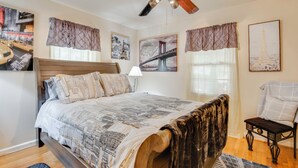 A bedroom with a bed, a chair, a ceiling fan, and artwork on the walls. - Peaceful Porch, Yard! Riverdale Home Near Dtwn ATL (Riverdale)
