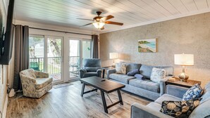 A living room with a ceiling fan, a sofa, a chair, a coffee table, and a lamp. - Walk to Ocean! Family PCB Condo w/ Balcony & Views (Panama City Beach)