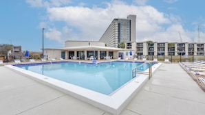 A rectangular pool with a white border, surrounded by lounge chairs and a covered seating area. - Walk to Ocean! Family PCB Condo w/ Balcony & Views (Panama City Beach)